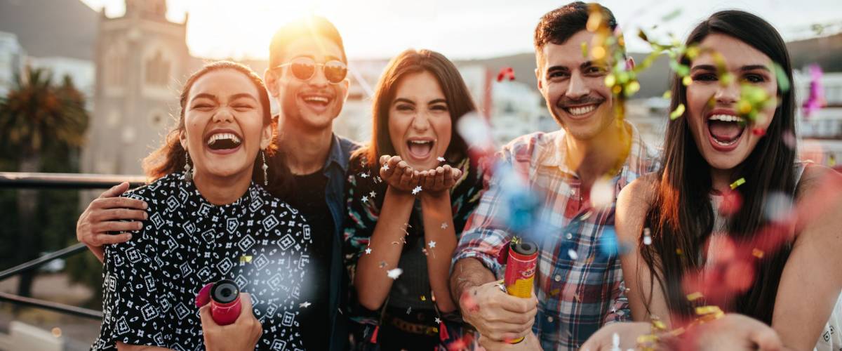 Group of friends enjoying party and throwing confetti. Friends having fun at rooftop party.
