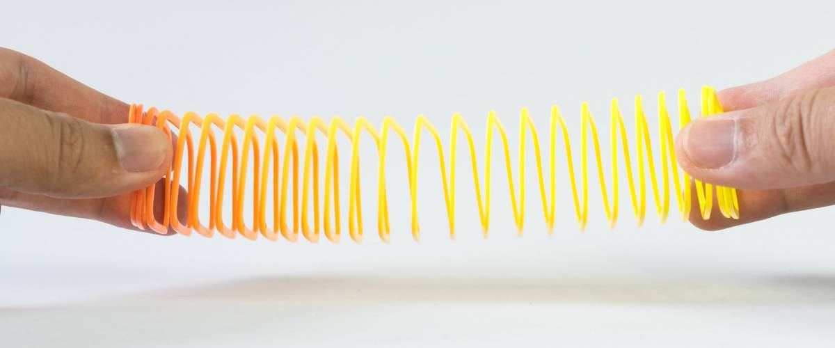 Hand holding elastic spring coil on empty background. Concept of business flexibility. Slightly de-focused and close-up shot. Copy space.
