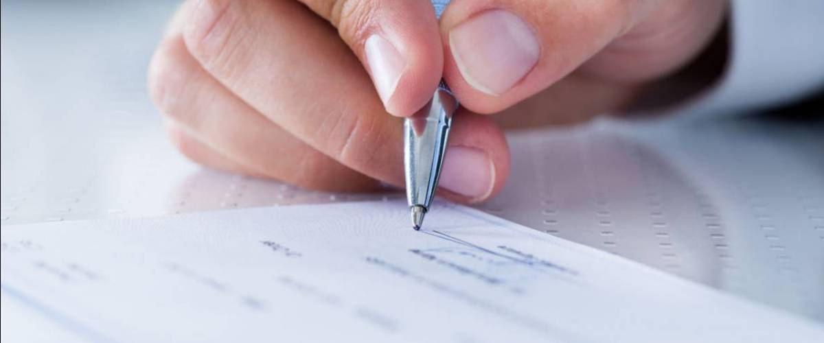 Hand of person signing a cheque
