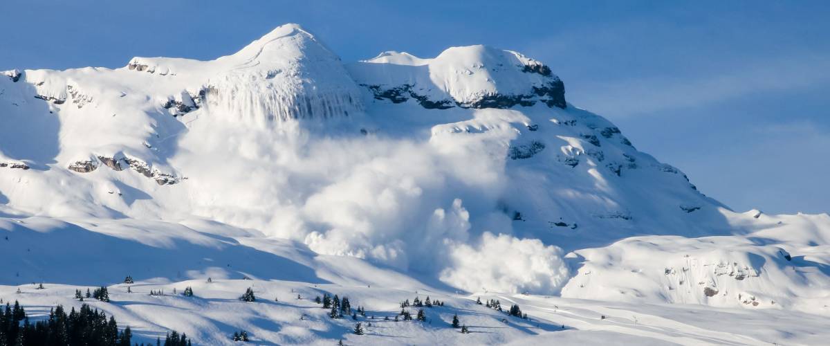 Huge real avalanche in the French Alps with the moon and blue sky