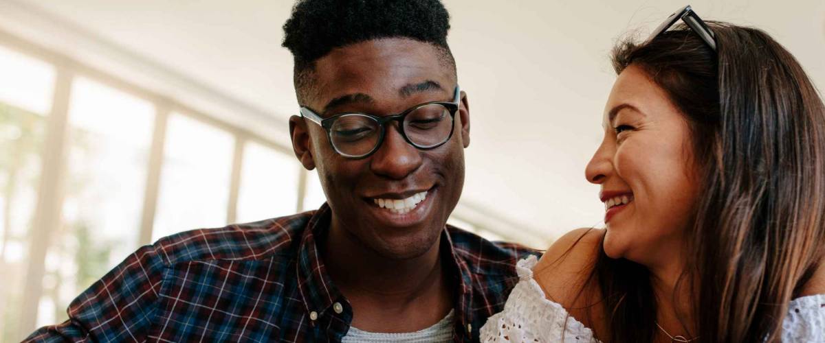 Happy interracial couple looking at their new house lease agreement and smiling with estate broker. Young couple renting a new house.