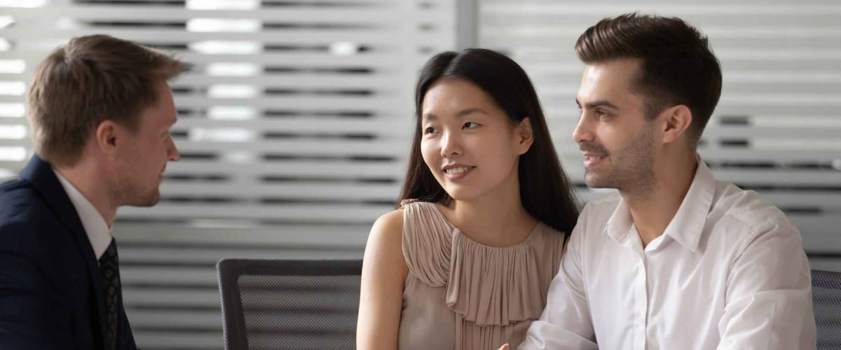 Happy mixed ethnicity couple customers talk to businessman