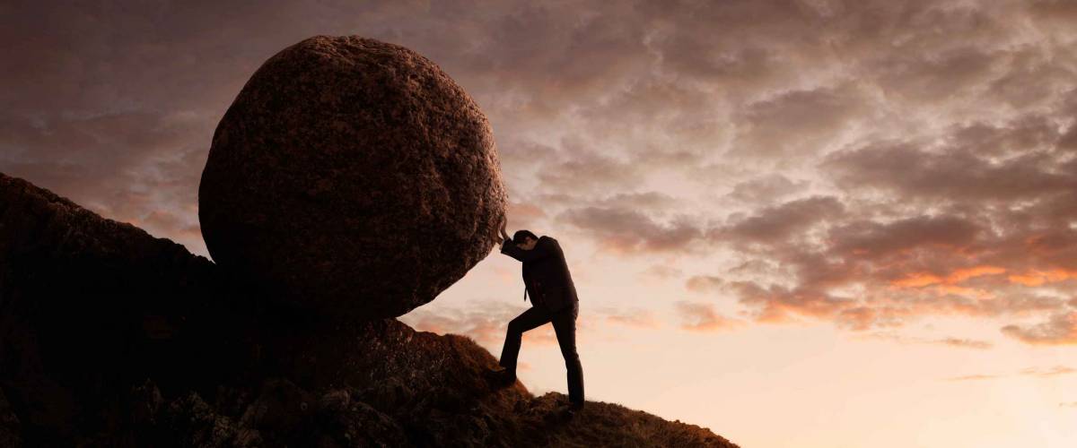 Business concept, Young businessman pushing large stone uphill with copy space