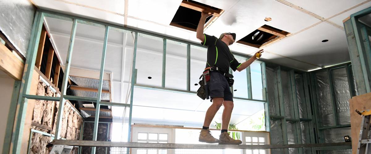 Construction worker replaces ceiling tiles.