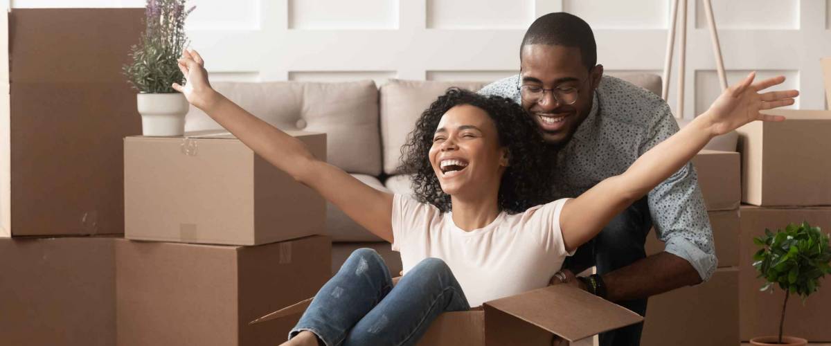 Happy african american young couple first time home buyers having fun unpacking