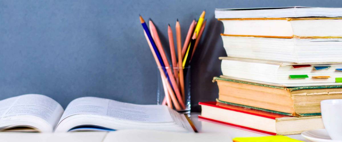Open textbook and hardback stacked with pencils on the table. The concept of intelligence comes from education. focused on the textbook.
