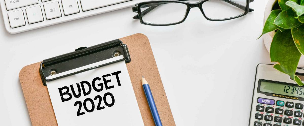 Budget 2020 text concept. Office workplace table with calculator, glasses, textbook and keyboard, budget 2020.