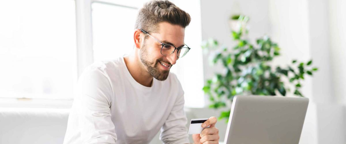 A Happy man buying online in his living room with laptop