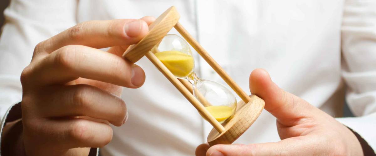 Hourglass in the hands of a businessman in a white shirt.