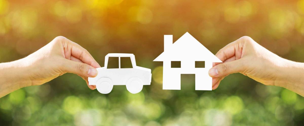 Woman hand holding home and car with paper art filed together on bokeh background in the public park, Loans for buying a house vs buying a car before anything good concept.