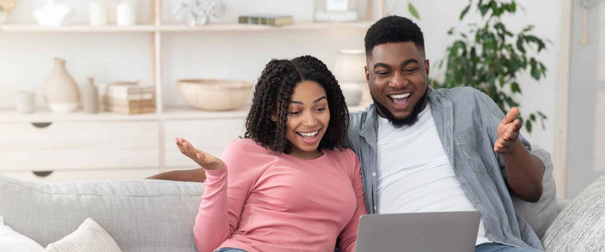 Great Internet Offer. Happy Black Couple Using Laptop At Home And Exclaiming With Excitement, Looking At Computer Screen, Free Space