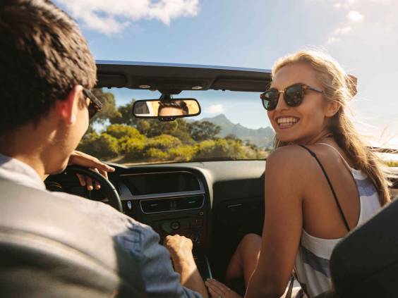 Beautiful woman going on a roadtrip with her boyfriend. Couple going on a long drive in a convertible car.