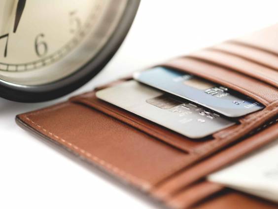 Credit cards in a wallet with a clock in the background.