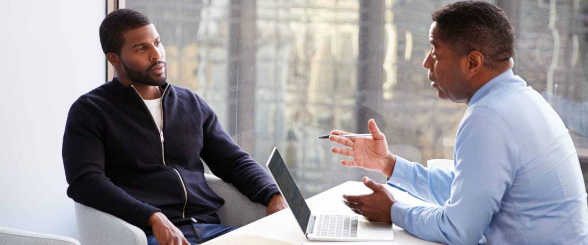 Man Meeting With Male Financial Advisor Relationship Counsellor In Office