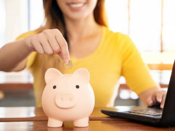 Woman dropping coins into a pink piggy bank