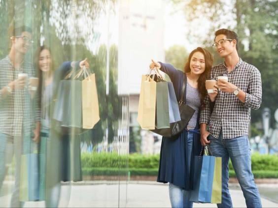 Smiling young woman showing something interesting in shop window to her boyfriend