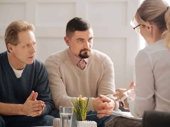 Two men consult with financial planner, look serious.