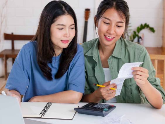 Two women looking at a receipt, discussing finances.