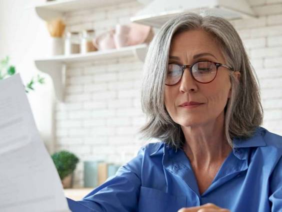 Senior mature business woman holding paper bill.