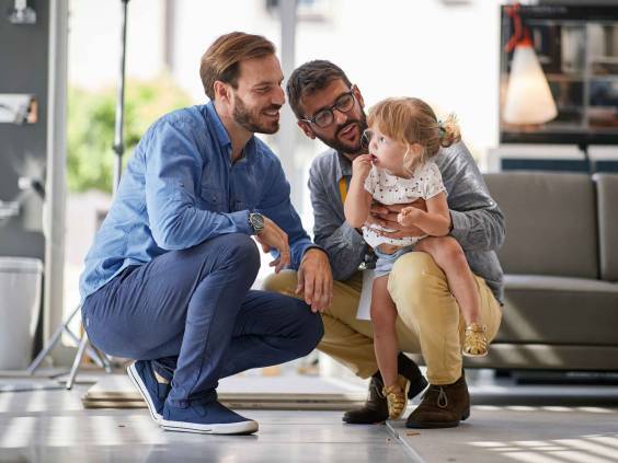 gay parents with child girl in store for household