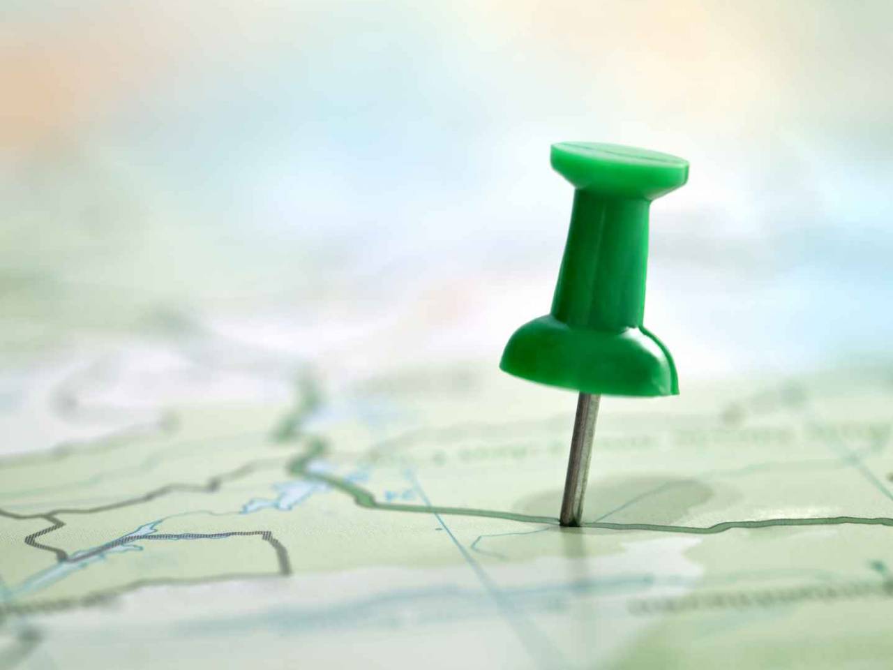 Pushpin showing the location of a destination point on a green map