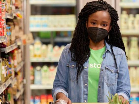 Woman shopping in an Instacart t-shirt in a grocery store, wearing mask.
