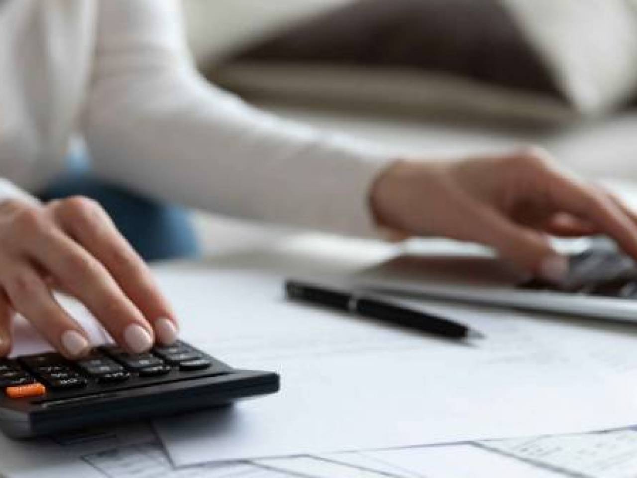 Close up of woman busy paying bills online on computer calculating household finances or taxes on machine, female manage home family expenditures, using calculator, make payment on laptop