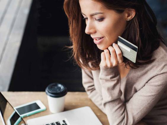 Young woman holding credit card and using laptop computer. Businesswoman or entrepreneur working at home. Online shopping, e-commerce, internet banking, spending