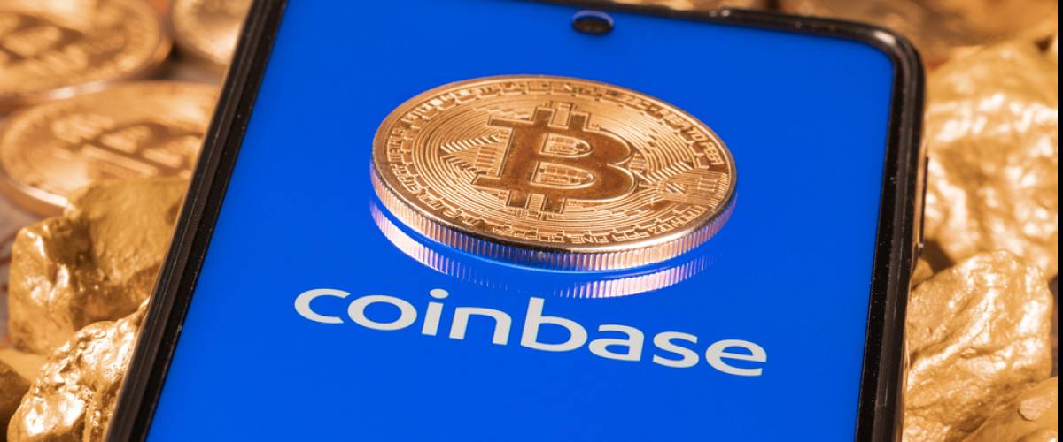 Coinbase crypto exchange logo on screen with Bitcoin coins.