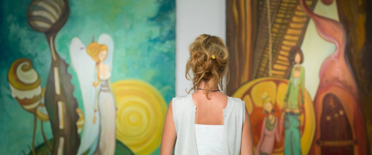 woman standing in an art gallery in front of two large colorful paintings