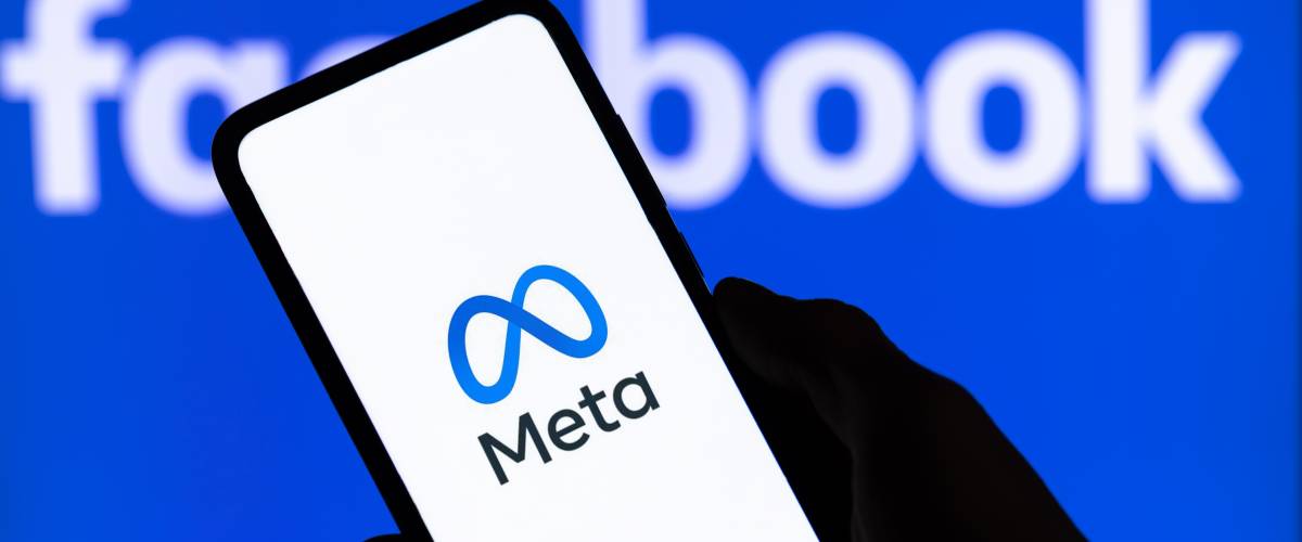 Metaverse logo on phone screen in front of facebook logo