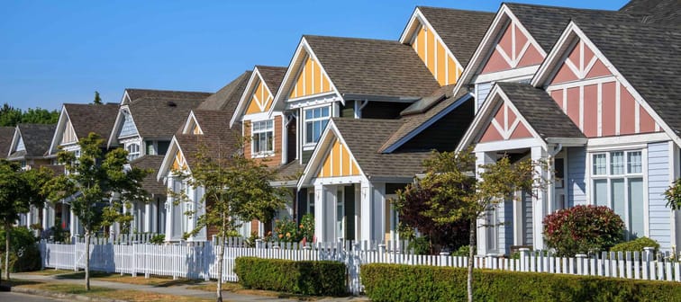 A row of a new houses in Richmond, British Columbia, Canada. Front yards of the houses and street with trees and bushes.