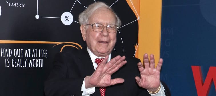 Warren Buffett holds up his hands to the camera.