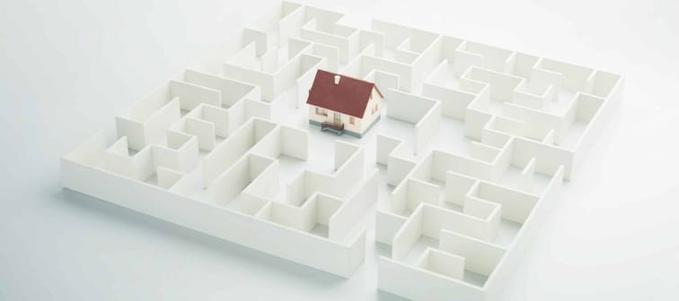 Real estate labyrinth. Toy house hidden inside a maze