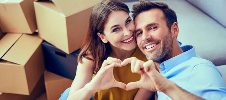 Happy couple during moving house showing heart sign