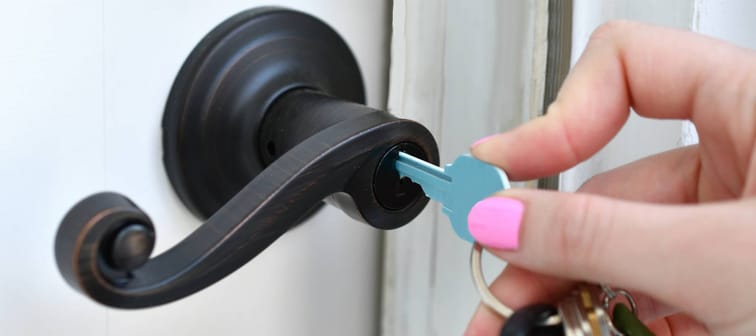 Blue key unlocking front door of new house