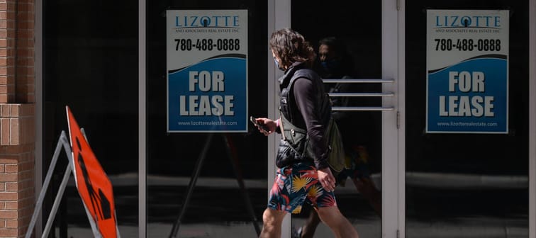 Man walking by empty storefront, business for lease in Toronto
