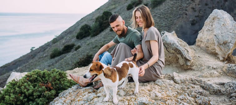 Happy young couple with their dog taking a break from hiking