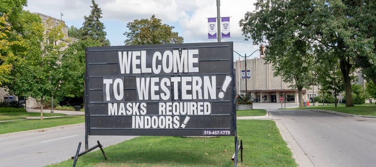 A sign saying WELCOME TO WESTERN! MASKS REQUIRED INDOORS! is seen at one of the gate to Western University campus in London, Ontario, Canada.