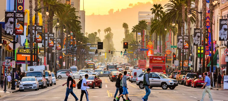 Traffic and pedestrians on Hollywood Boulevard at dusk.