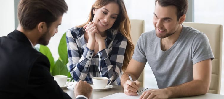 Young couple signs personal loan contract with banker.