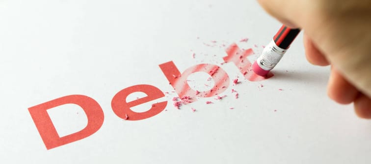 Close up of red pencil erasing the word debt on paper